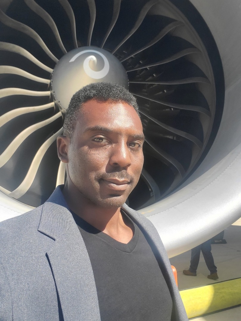 Christopher Williams standing beside an aircraft engine